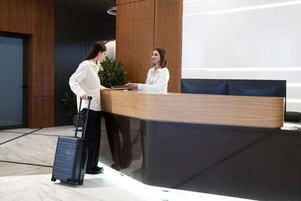 donna alla reception di un hotel che trasporta valigie