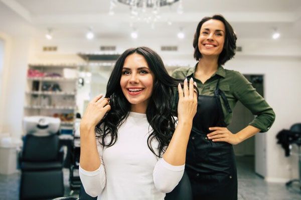 Foto ravvicinata di una parrucchiera che tocca i capelli felici della sua cliente mentre le fa una nuova acconciatura