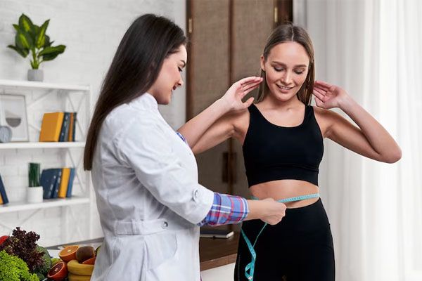 Nutritionist in her office measures her patient's waist circumference