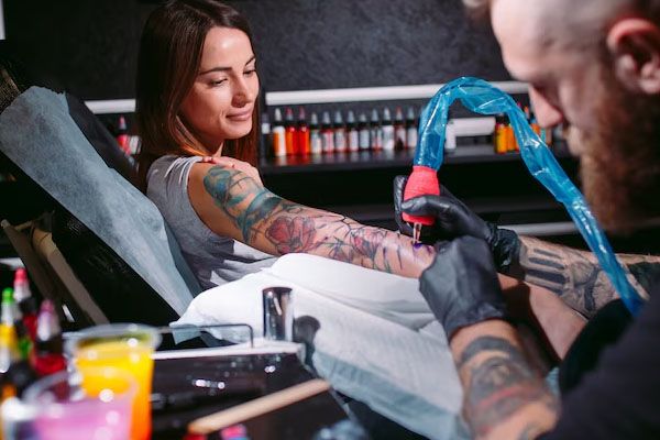 Un tatuatore professionista tatua la mano di una ragazza