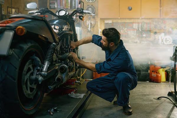 Un giovane uomo indossa una tuta e utilizza strumenti professionali mentre lavora in un'officina di riparazi