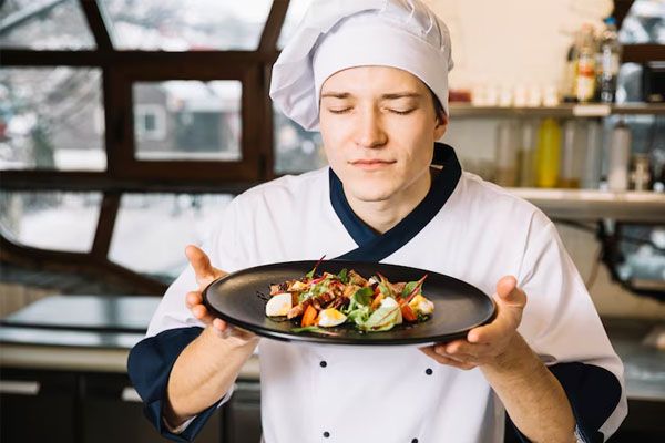 chef che annusa un piatto che tiene in mano
