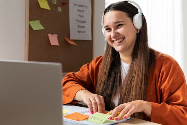 giovane sorridente con le cuffie davanti al computer