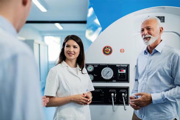 Paziente e medico in piedi e a parlare davanti a una camera iperbarica