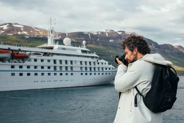 Un fotografo scatta foto di una nave da crociera in un fiordo