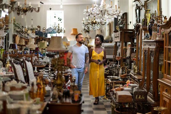Uomo e donna che camminano tra oggetti d'antiquariato