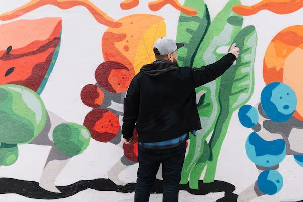 Vista posteriore di un uomo che fa graffiti con vernice spray su un muro