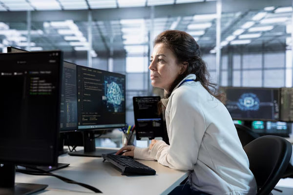 Donna seduta davanti a diversi monitor in un ufficio