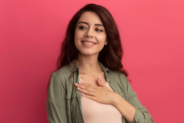 Una giovane donna sorridente si mette una mano sul petto