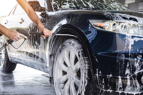 Uomo che lava l'auto con l'idropulitrice