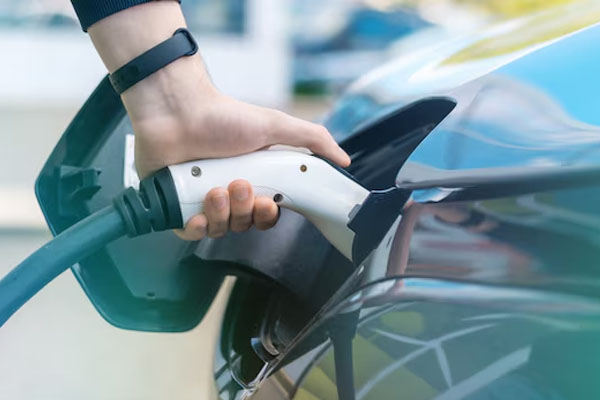 Primo piano di una mano che inserisce un caricabatterie su un'auto elettrica