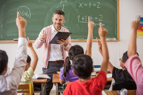 Un insegnante in classe con i suoi studenti che alzano la mano