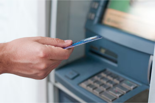 La mano di una persona che usa un bancomat